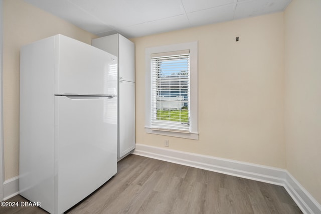 kitchen with white cabinetry, light hardwood / wood-style floors, and white fridge