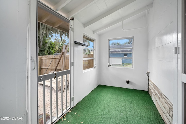 unfurnished sunroom featuring golf simulator and vaulted ceiling with beams