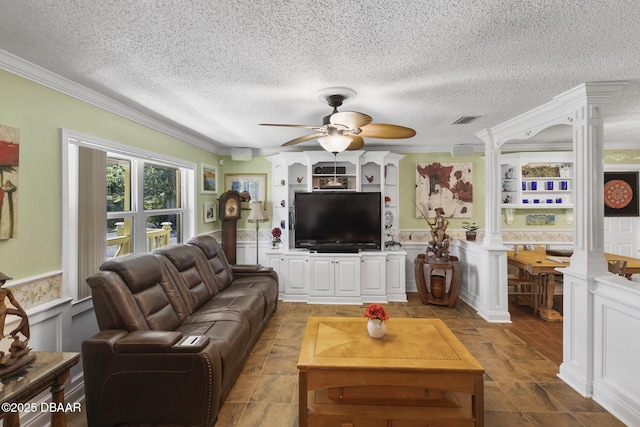 living area with visible vents, ceiling fan, ornamental molding, wainscoting, and ornate columns