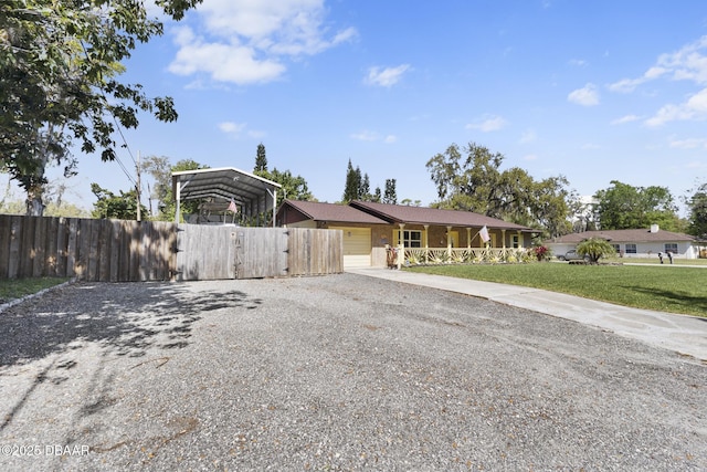 view of front facade featuring a detached carport, driveway, a front lawn, and fence