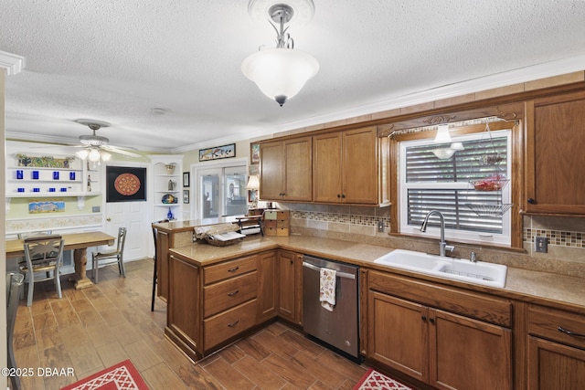 kitchen featuring a sink, brown cabinets, a peninsula, and stainless steel dishwasher