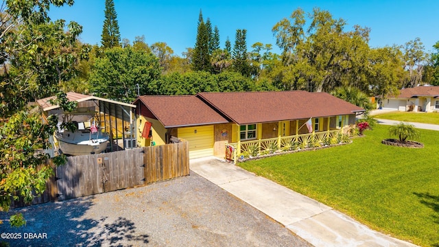 view of front facade with a front yard, a gate, fence, covered porch, and concrete driveway