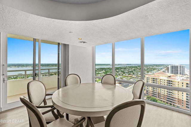 2545 S Atlantic Ave Unit 0102, Daytona Beach Shores, FL 32118 - dining space with light wood-style floors, floor to ceiling windows, healthy amount of natural light, a city view, and a textured ceiling