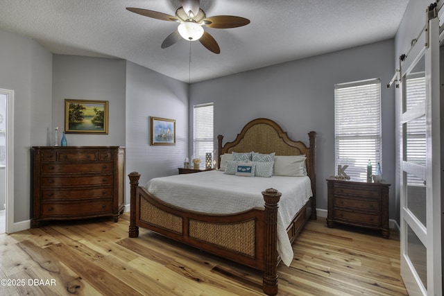 bedroom with ceiling fan, a textured ceiling, and light hardwood / wood-style floors