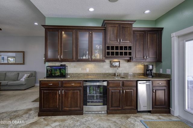 kitchen with sink, light stone counters, wine cooler, and dark brown cabinetry