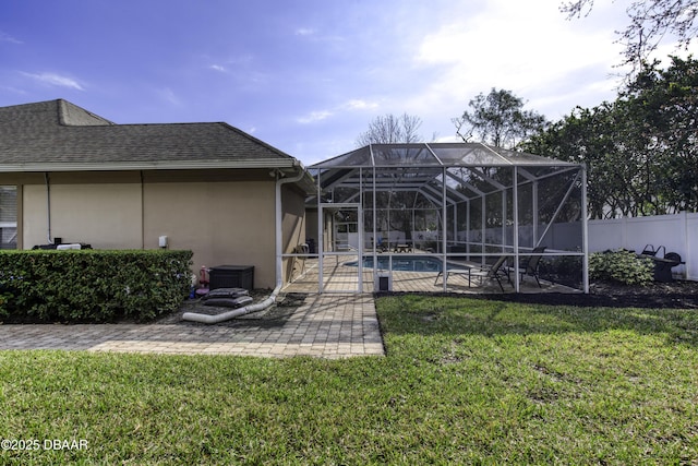 rear view of property featuring a fenced in pool, a yard, a patio, and glass enclosure