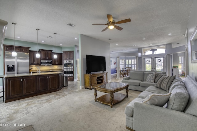 carpeted living room with ceiling fan, sink, and a textured ceiling