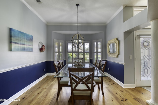 dining space with ornamental molding, wood-type flooring, and a chandelier