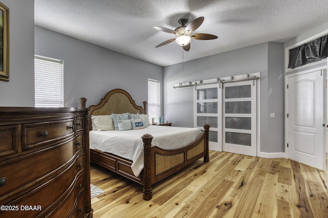 bedroom with ceiling fan, a textured ceiling, and light wood-type flooring