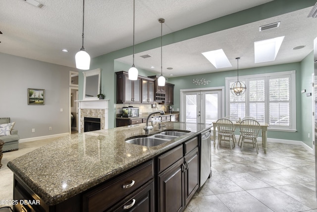 kitchen featuring pendant lighting, sink, dishwasher, and a center island with sink