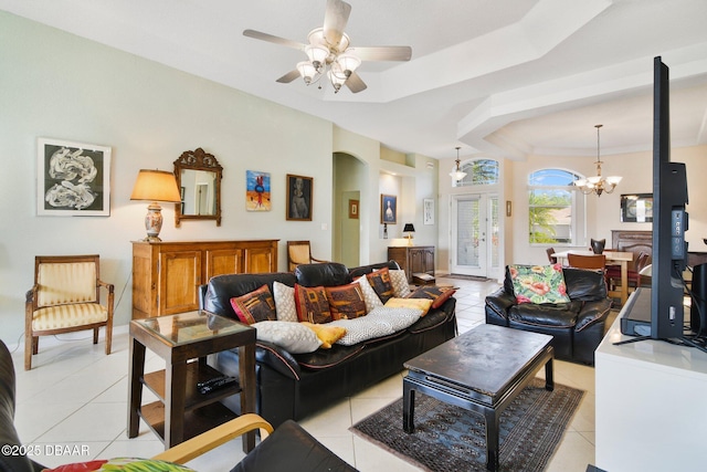 tiled living room featuring ceiling fan with notable chandelier and a tray ceiling