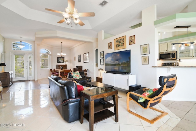 tiled living room featuring crown molding, ceiling fan with notable chandelier, and a tray ceiling