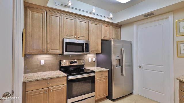 kitchen featuring decorative backsplash, light stone countertops, appliances with stainless steel finishes, and light tile patterned floors