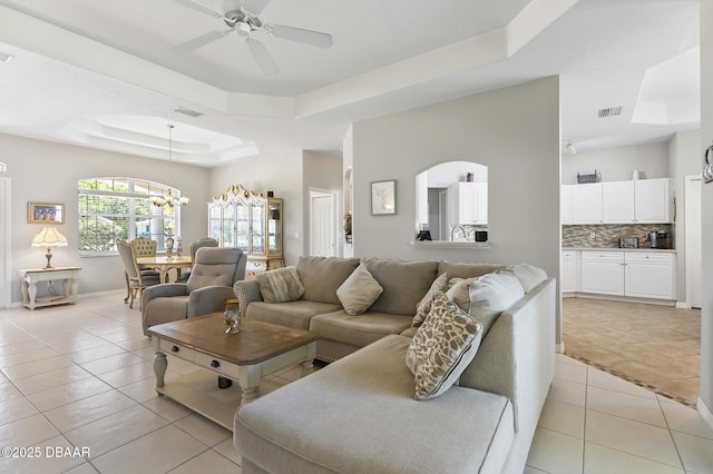 73 Foxhall Ln, Palm Coast, FL 32137 - living area with a tray ceiling, light tile patterned floors, a chandelier, a ceiling fan, and baseboards