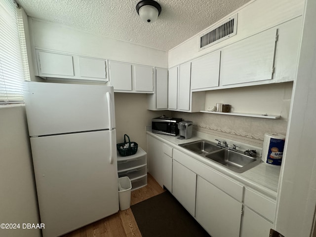 kitchen with white cabinets, dark hardwood / wood-style floors, white fridge, and sink