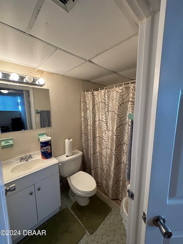 bathroom with a drop ceiling, vanity, toilet, and a shower with shower curtain