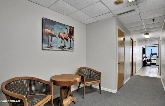 hall featuring light carpet and a drop ceiling