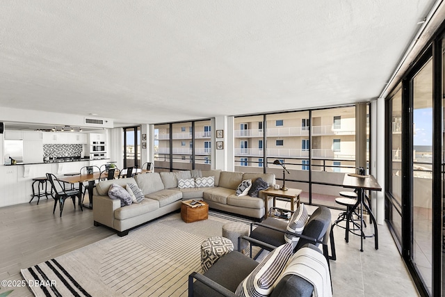 living room with a healthy amount of sunlight, a wall of windows, and a textured ceiling