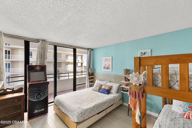 bedroom with expansive windows, light hardwood / wood-style floors, and a textured ceiling