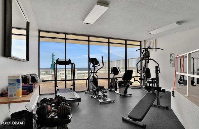 exercise room with plenty of natural light, floor to ceiling windows, a water view, and a textured ceiling