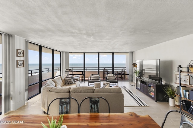 living room with a beach view, a water view, and a wall of windows