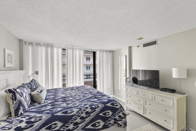 bedroom with a textured ceiling and light hardwood / wood-style flooring