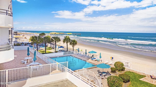 view of pool with a water view, a beach view, and a patio