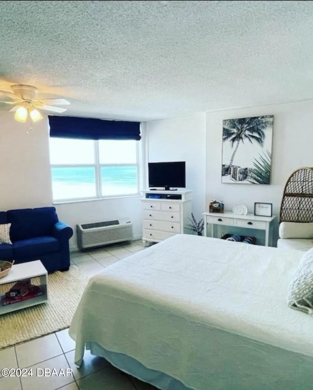 bedroom with an AC wall unit, a textured ceiling, light tile patterned floors, and ceiling fan