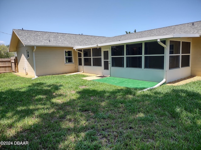 back of property with fence, a lawn, roof with shingles, and a sunroom