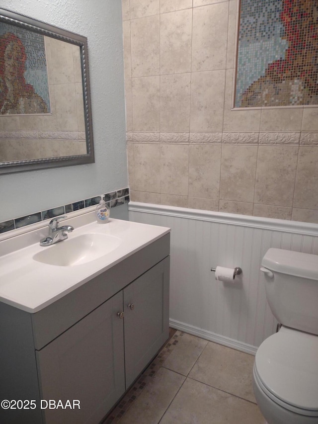 half bath featuring vanity, tile patterned floors, and toilet