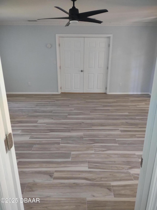 unfurnished bedroom with baseboards, wood finished floors, and crown molding