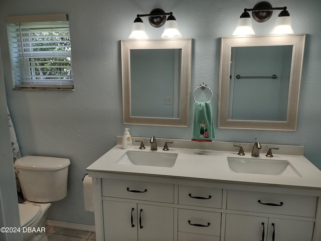 full bath with double vanity, toilet, tile patterned floors, and a sink