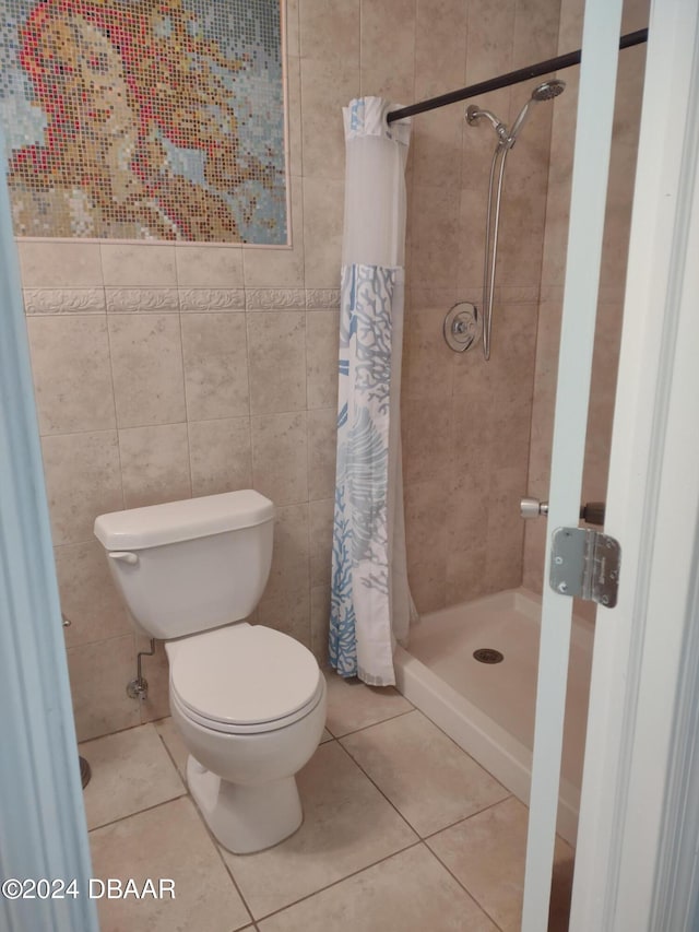 bathroom with tile patterned floors, toilet, tile walls, and a stall shower