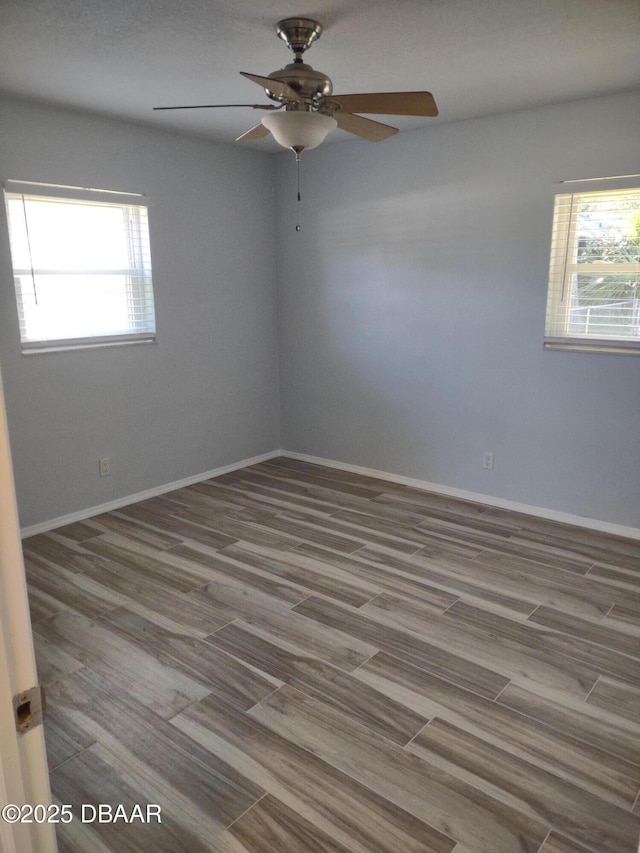 unfurnished room with a ceiling fan, baseboards, and wood finished floors