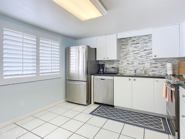 kitchen featuring white cabinetry, appliances with stainless steel finishes, light tile patterned floors, sink, and decorative backsplash