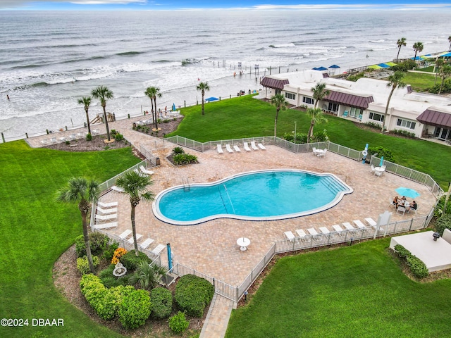 view of swimming pool with a patio, a water view, and a lawn