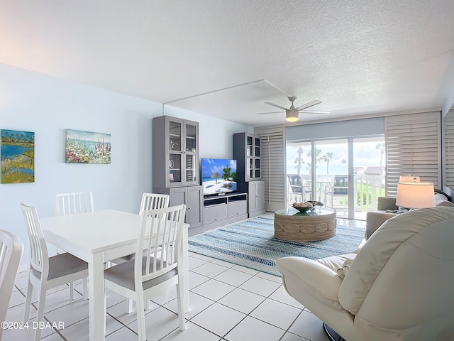 living room featuring a textured ceiling, light tile patterned floors, and ceiling fan