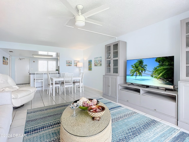 living room featuring light tile patterned flooring, a textured ceiling, and ceiling fan