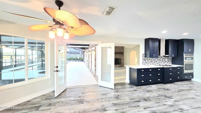 3128 John Anderson Dr, Ormond Beach, FL 32176 - kitchen featuring dark cabinetry, double oven, backsplash, light countertops, and a ceiling fan