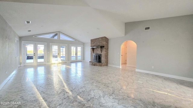 3128 John Anderson Dr, Ormond Beach, FL 32176 - unfurnished living room with french doors, vaulted ceiling, light marble finish floors, arched walkways, and a brick fireplace