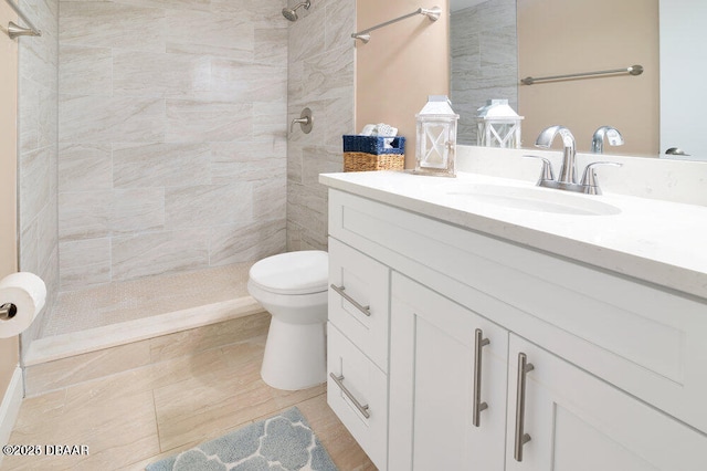 bathroom featuring vanity, tiled shower, and toilet