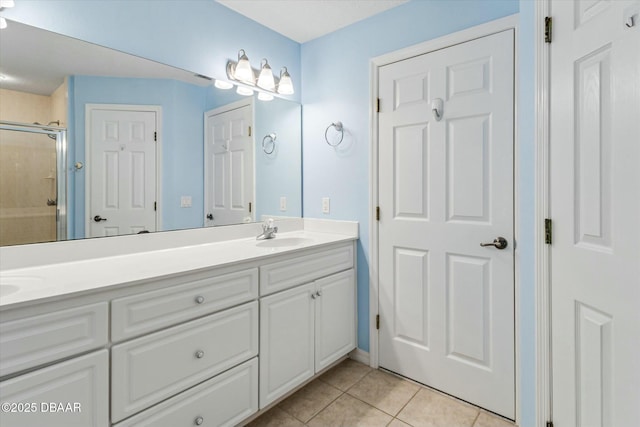 full bathroom featuring tile patterned floors, a sink, a shower with door, and double vanity