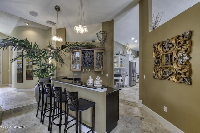 7 Foxfords Chase, Ormond Beach, FL 32174 - indoor wet bar featuring stone tile floors, stainless steel fridge, a chandelier, lofted ceiling, and decorative light fixtures