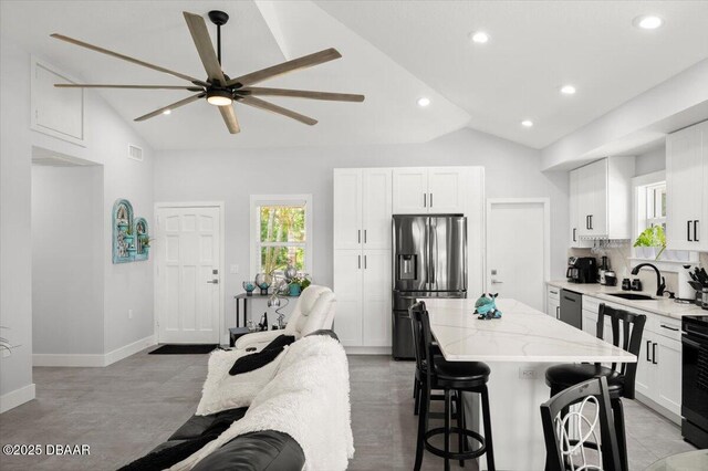 5967 Riverside Dr, Port Orange, FL 32127 - kitchen with appliances with stainless steel finishes, a kitchen island, ceiling fan, a kitchen bar, and high vaulted ceiling