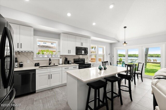 5967 Riverside Dr, Port Orange, FL 32127 - kitchen featuring black appliances, lofted ceiling, decorative backsplash, a kitchen breakfast bar, and recessed lighting