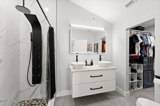 5967 Riverside Dr, Port Orange, FL 32127 - full bath with a marble finish shower, vaulted ceiling, double vanity, and a spacious closet