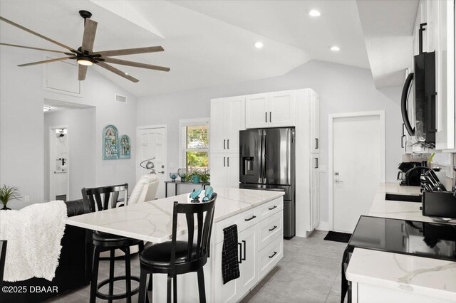 5967 Riverside Dr, Port Orange, FL 32127 - kitchen with stainless steel fridge with ice dispenser, black microwave, a ceiling fan, a kitchen breakfast bar, and light stone countertops
