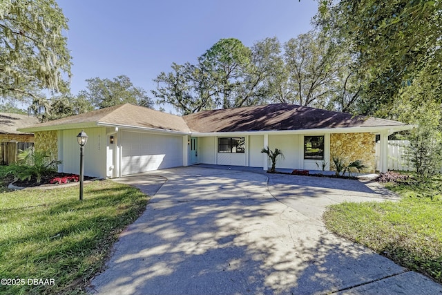 single story home with concrete driveway, stone siding, an attached garage, fence, and a front yard