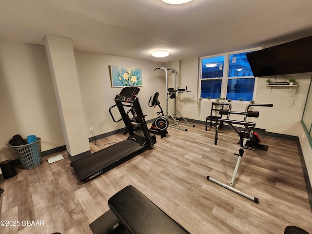 exercise area featuring baseboards and wood finished floors