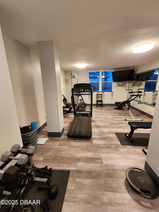 workout area with baseboards and wood finished floors